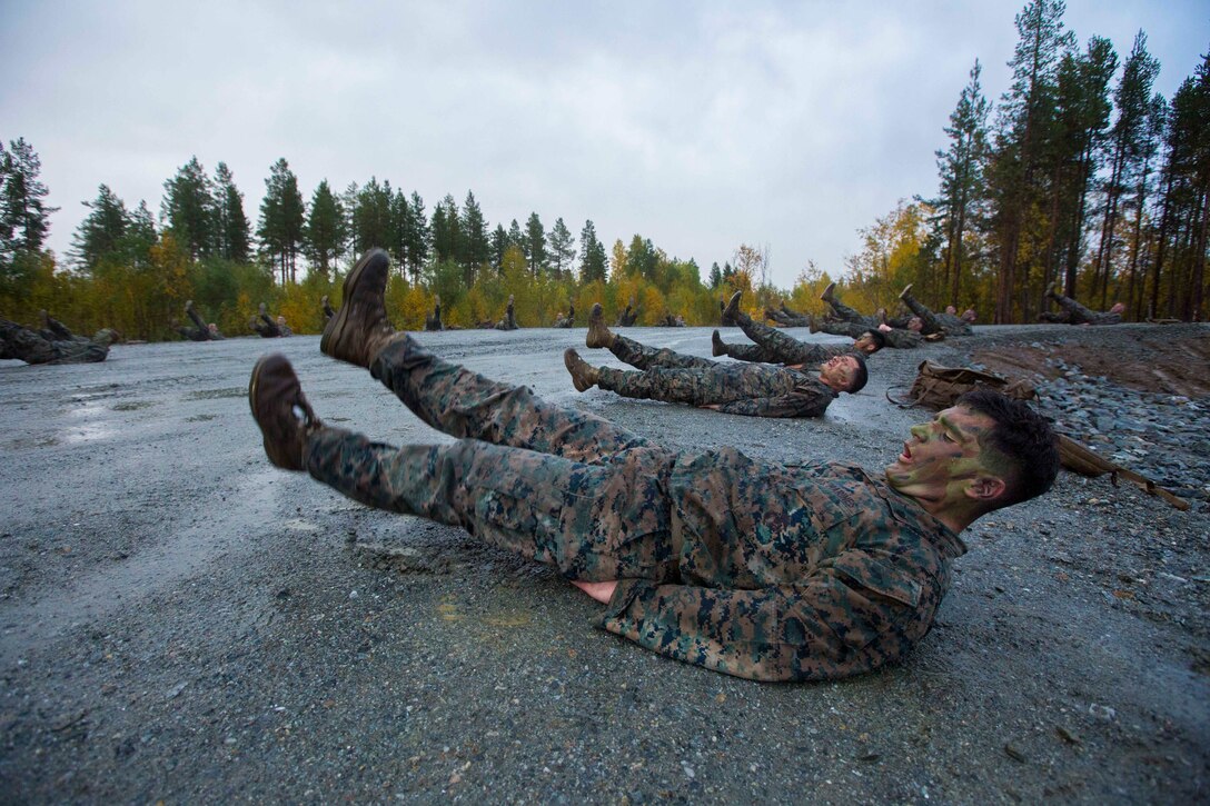 Marines lie on the ground with their legs in the air.