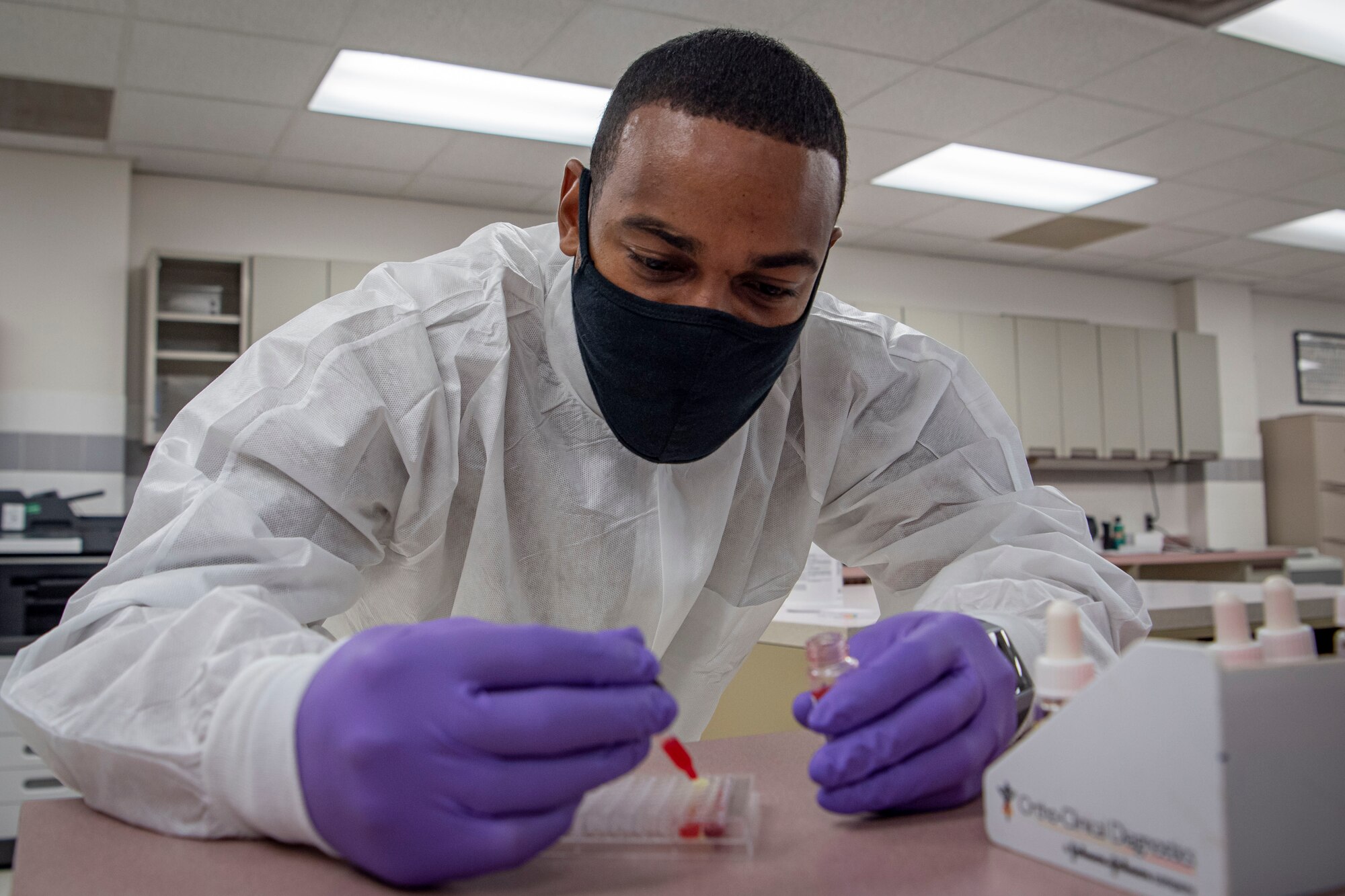 Photo of a sailor dropping a reagent into an assay plate.