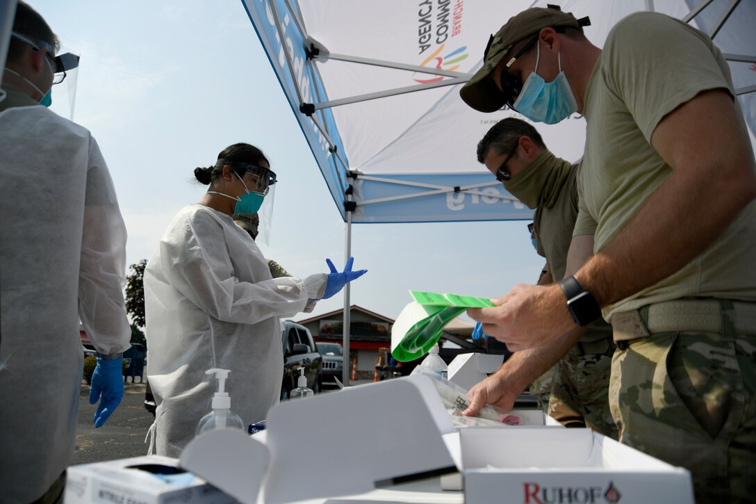 A group of service members stand around a long table with boxes on it.