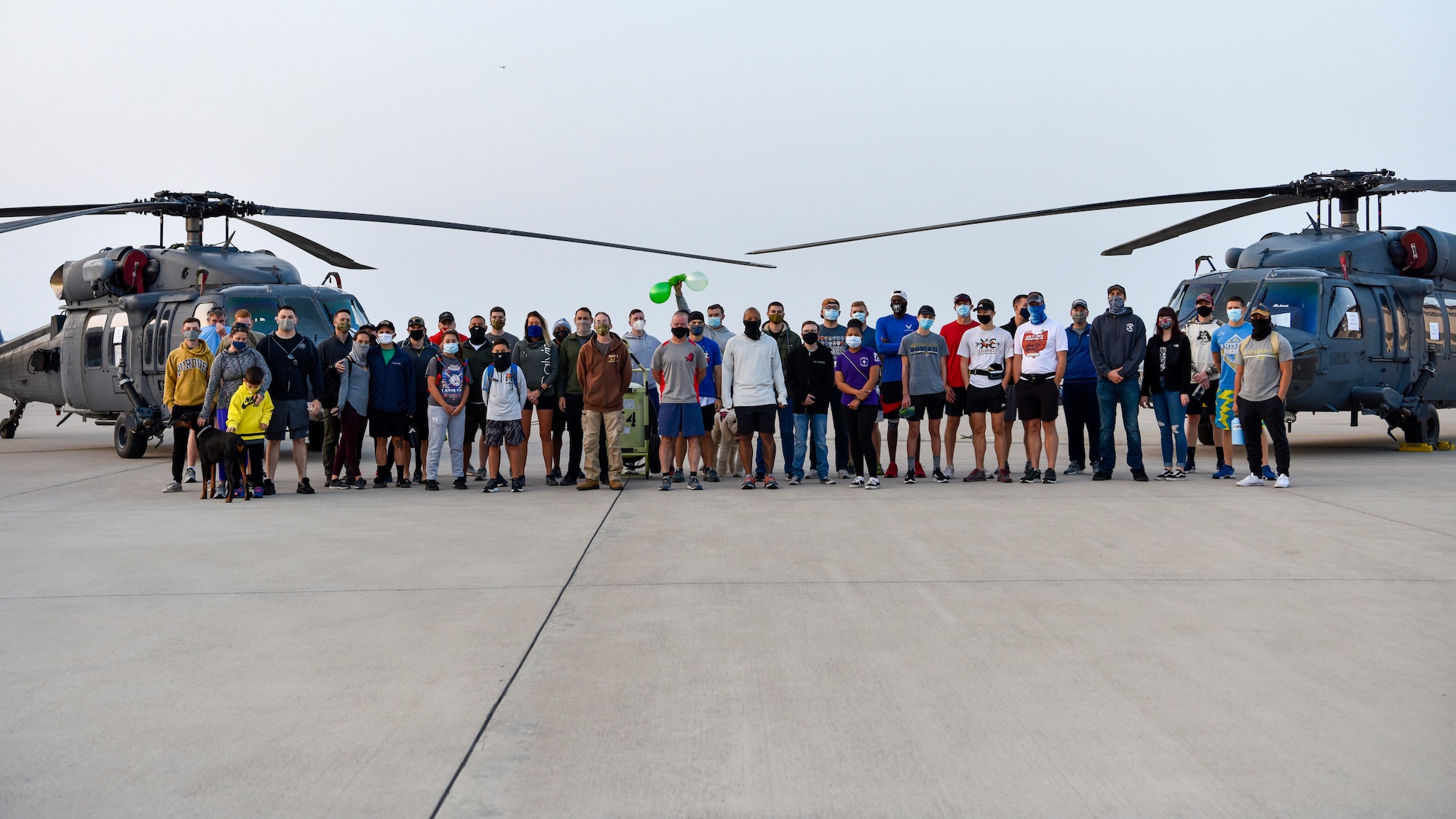 Group photo of 40 people standing between two helicopters.