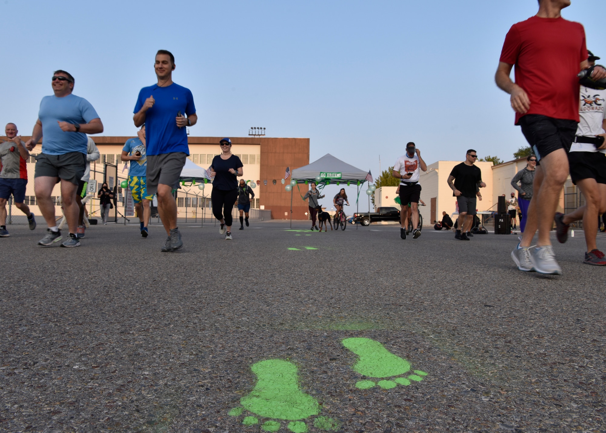 Group of people spread out and running towards green feet painted on the ground.