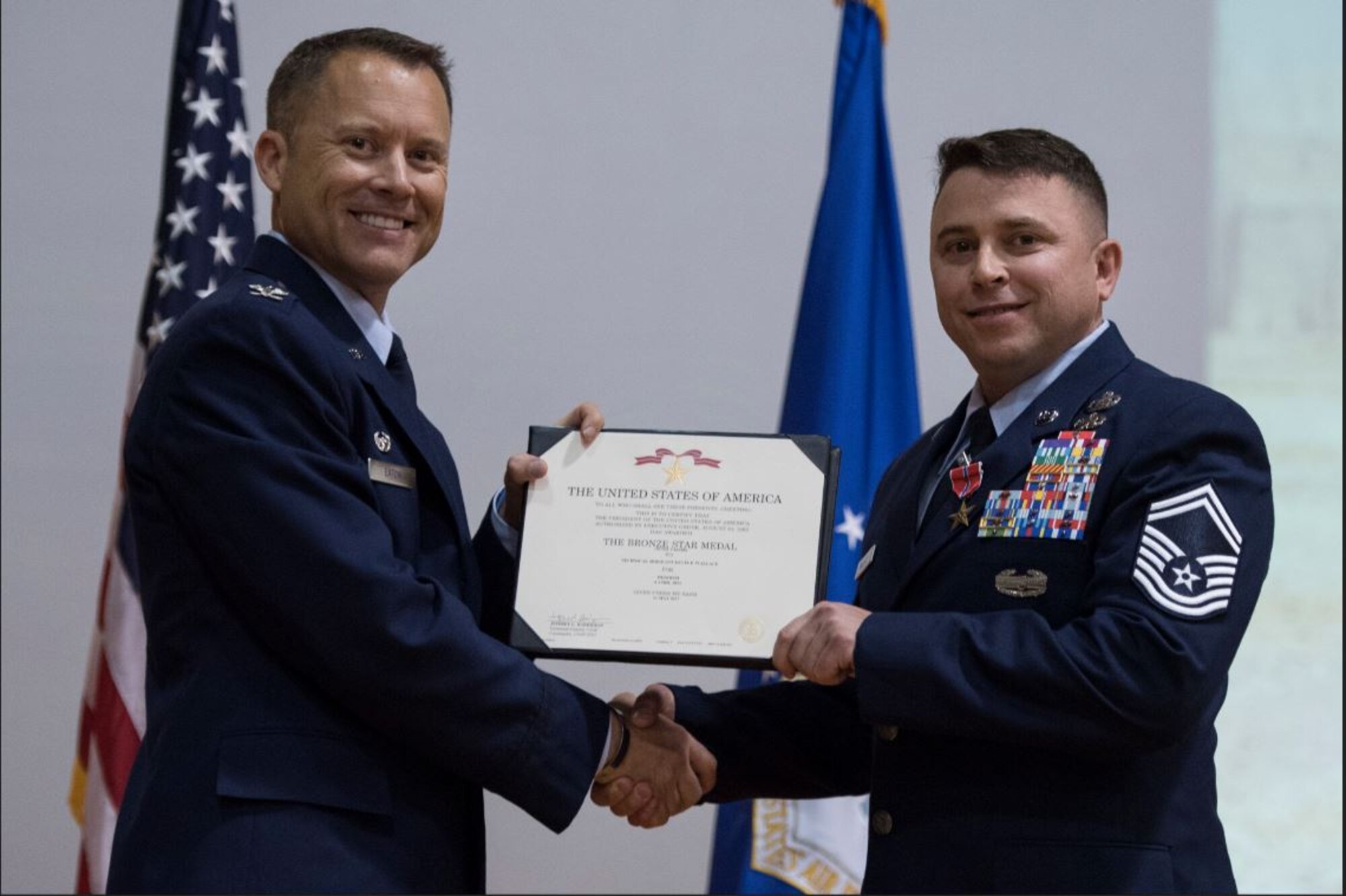 Col. Casey D. Eaton, left, then-89th Airlift Wing commander, awards Senior Master Sgt. Kevin Wallace, then-89th AW public affairs chief, with a Bronze Star with Valor medal at Joint Base Andrews, Md., Aug. 15, 2017. Wallace was awarded the medal for his distinguished heroism on April 4, 2011, as a 4th Infantry Division combat photographer. Wallace, a retired senior master sergeant, shared his personal story of resilience with the Hanscom community during a virtual Suicide Prevention Month Storytellers event Sept. 22. (U.S. Air Force photo by Airman 1st Class Valentina Lopez)