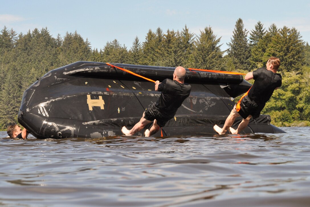 Army National Guardsmen stand on an inflatable boat in a lake holding ropes.