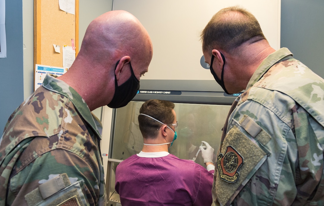 Chief Master Sgt. Chris Simpson, 18th Air Force command chief, and Maj. Gen. Thad Bibb, 18th Air Force commander, watch Staff Sgt. Hunter Meir, 436th Medical Support Squadron shipping noncommissioned officer in charge, process a COVID-19 nasal swab sample Sept. 23, 2020, at Dover Air Force Base, Delaware. Maj. Gen. Thad Bibb, 18th Air Force commander, and Chief Master Sgt. Chris Simpson, 18th Air Force command chief, learned how the 436th Medical Group continues to battle COVID-19. (U.S. Air Force photo by Roland Balik)