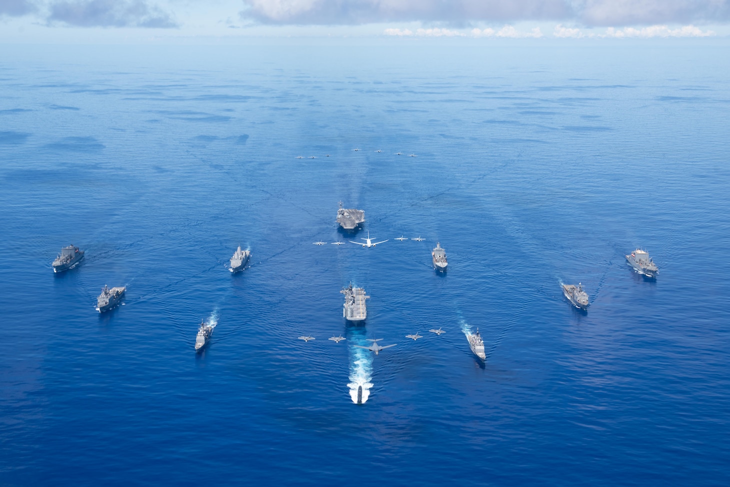 PHILIPPINE SEA (Sept. 25, 2020) From left, USNS Charles Drew (T-AKE 10), USS Comstock (LSD 45), USS Shiloh (CG 67), USS New Orleans (LPD 18), USS Chicago (SSN 721), USS America (LHA 6), USS Ronald Reagan (CVN 76), USNS John Ericsson (T-AO 194), USS Antietam (CG 54), USS Germantown (LSD 42), and USNS Sacagawea (T-AKE 2) steam in formation while E/A-18G Growlers and FA-18E Super Hornets from Carrier Air Wing (CVW) 5, a P-8 Poseidon from Commander Task Force 72,  and U.S. Air Force F-22 Raptors and  a B-1B Bomber fly over the formation in support of Valiant Shield 2020. Valiant Shield is a U.S. only, biennial field training exercise (FTX) with a focus on integration of joint training in a blue-water environment among U.S. forces. This training enables real-world proficiency in sustaining joint forces through detecting, locating, tracking and engaging units at sea, in the air, on land and in cyberspace in response to a range of mission areas. (U.S. Navy photo by Mass Communication Specialist 3rd Class Jason Tarleton)