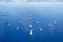 PHILIPPINE SEA (Sept. 25, 2020) From left, USNS Charles Drew (T-AKE 10), USS Comstock (LSD 45), USS Shiloh (CG 67), USS New Orleans (LPD 18), USS Chicago (SSN 721), USS America (LHA 6), USS Ronald Reagan (CVN 76), USNS John Ericsson (T-AO 194), USS Antietam (CG 54), USS Germantown (LSD 42), and USNS Sacagawea (T-AKE 2) steam in formation while E/A-18G Growlers and FA-18E Super Hornets from Carrier Air Wing (CVW) 5, a P-8 Poseidon from Commander Task Force 72,  and U.S. Air Force F-22 Raptors and  a B-1B Bomber fly over the formation in support of Valiant Shield 2020. Valiant Shield is a U.S. only, biennial field training exercise (FTX) with a focus on integration of joint training in a blue-water environment among U.S. forces. This training enables real-world proficiency in sustaining joint forces through detecting, locating, tracking and engaging units at sea, in the air, on land and in cyberspace in response to a range of mission areas. (U.S. Navy photo by Mass Communication Specialist 3rd Class Jason Tarleton)