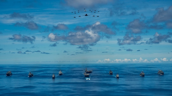 Ships participating in Valiant Shield 2020 steam in formation while E/A-18G Growlers and FA-18E Super Hornets from Carrier Air Wing (CVW) 5, a P-8 Poseidon assigned to Commander Task Force 72, and U.S. Air Force F-22 Raptors and a B-1B Bomber fly over the formation.