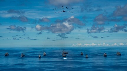 IMAGE: PHILIPPINE SEA (Sept. 25, 2020) - USNS Charles Drew (T-AKE 10), USS Comstock (LSD 45), USS Shiloh (CG 67), USS New Orleans (LPD 18), USS Chicago (SSN 721), USS America (LHA 6), USS Ronald Reagan (CVN 76), USNS John Ericsson (T-AO 194), USS Antietam (CG 54), USS Germantown (LSD 42) and USNS Sacagawea (T-AKE 2) steam in formation while E/A-18G Growlers, FA-18E Super Hornets, a P-8 Poseidon, U.S. Air Force F-22 Raptors and a B-1B Bomber fly over the formation in support of Valiant Shield 2020. Meanwhile, a team of Naval Surface Warfare Center Dahlgren Division (NSWCDD) scientists and engineers worked from two locations – Dahlgren, Va., and Honolulu, Hawaii – to ensure the success of this year’s Valiant Shield exercise. “Our biggest strategic accomplishment was supporting live forces, both afloat and at terrestrial sites, using a combined in-person and local operations team,” said Joseph Pack, NSWCDD deputy director for expeditionary warfare, regarding Dahlgren’s impact on the exercise that focuses on the integration of joint training in a blue-water environment among U.S. forces.  (U.S. Navy photo by Mass Communication Specialist 2nd Class Codie L. Soule)