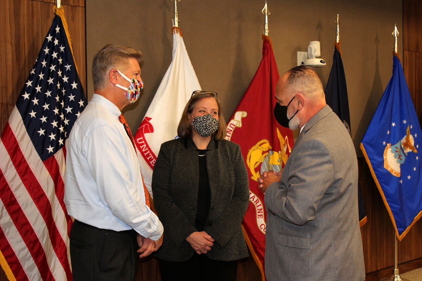 Three people wearing masks are having a conversation.