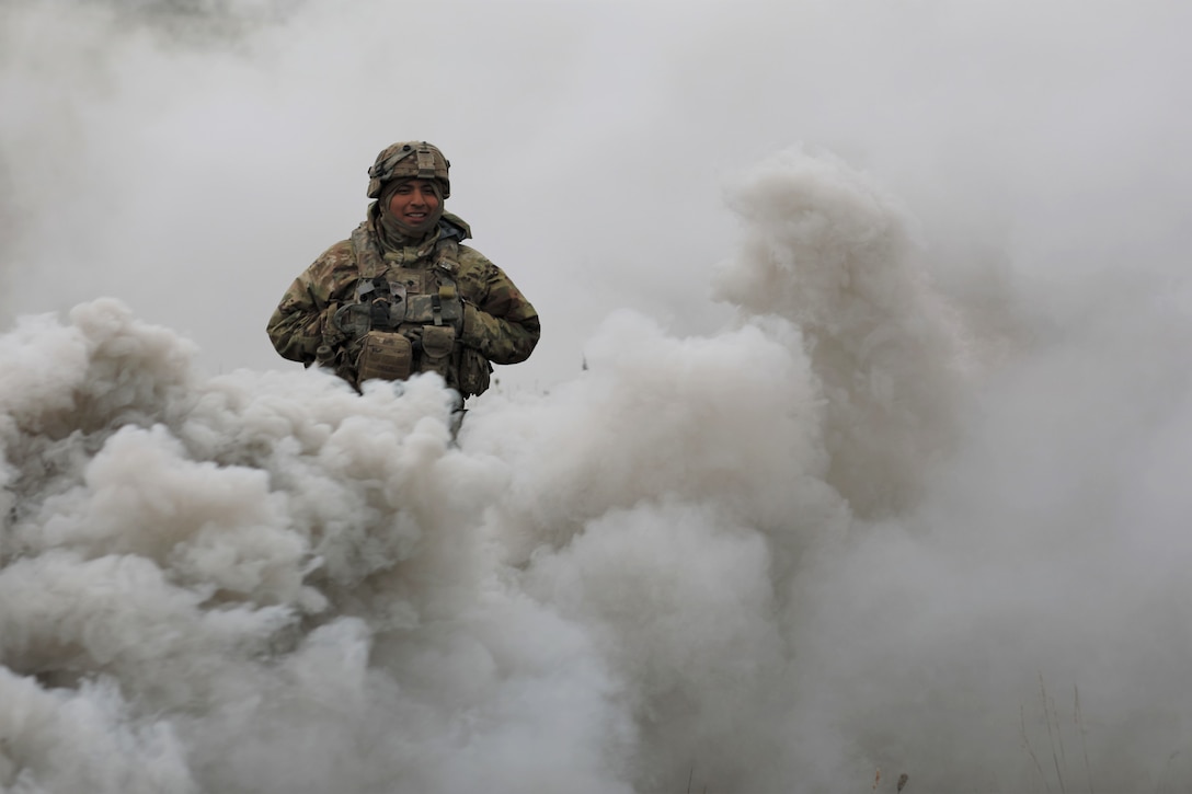 A soldier walks through smoke.