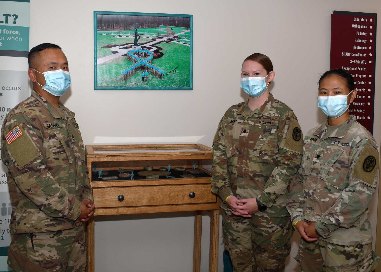 (From left to right) Staff Sgt. Dennis Manuel, primary care noncommissioned officer; Spc. Marissa Kirian, NCO in charge of OB/GYN; and Spc. Kelly Pham, laboratory medical specialist, stand in front of the Fort Drum Medical Activity’s Sexual Harassment and Assault Response and Prevention display at the Guthrie Army Medical Home on Fort Drum, N.Y. Sept. 23, 2020.  Manuel, Kirian and Kelly recently received training as Sexual Assault Medical Forensic Examiner (SAMFE) assists.  Under the new pilot program, the volunteer Soldiers will now be on call to assist with medical exams, collect forensic evidence, and support victims during sexual assault forensic exams (SAFE).