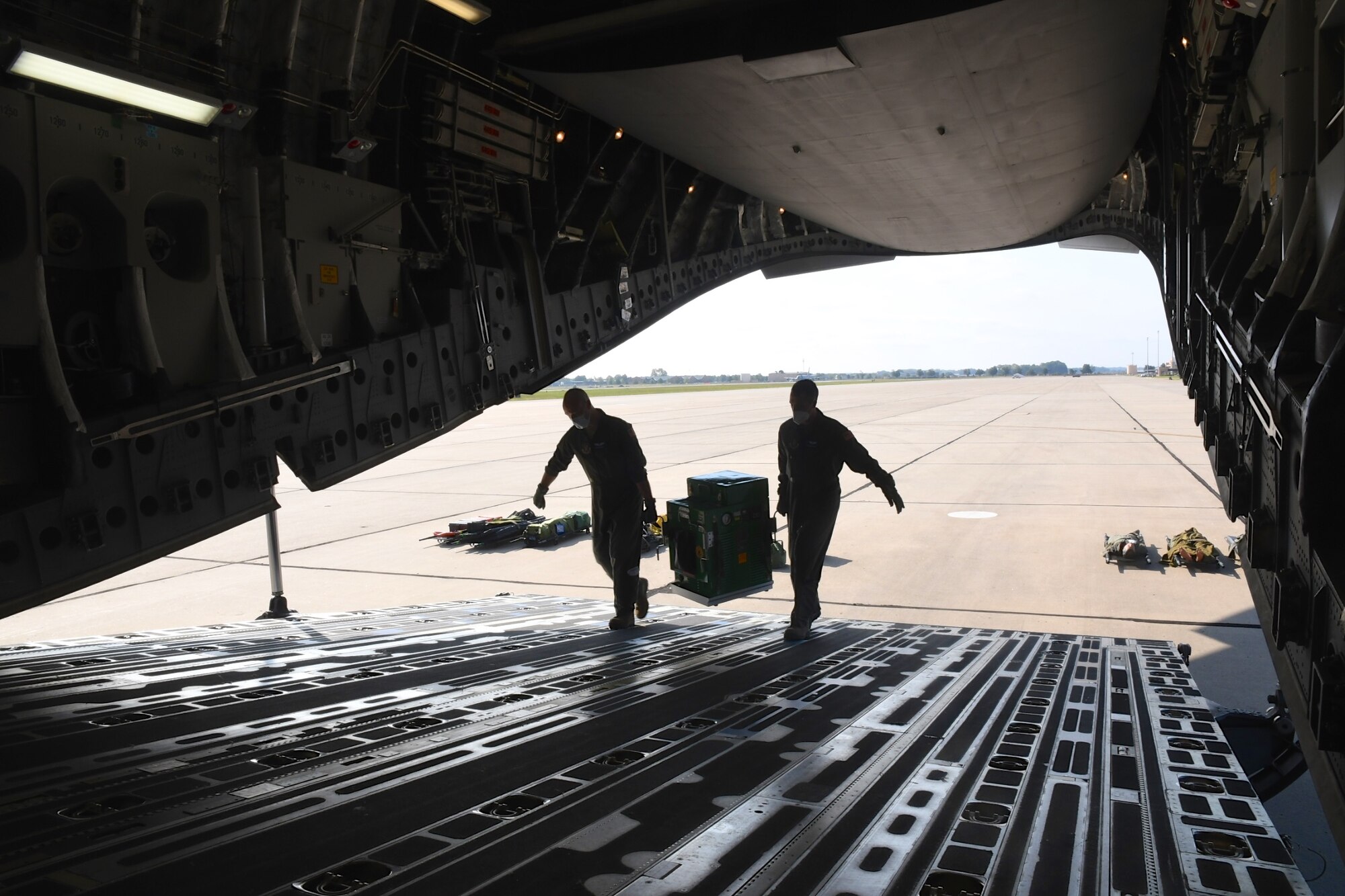 932nd Airlift Wing Aeromedical Evacuation Squadron (AES) personnel carry gear up the ramp as they train with a visiting C-17 aircraft on September 27, 2020, Scott Air Force Base, Ill. The 932nd Airlift Wing's AES worked improving and refining hands on skills at the reserve unit, which included visiting members of the 131st Medical Group from Missouri, and 445th Airlift Wing from Ohio. Airmen worked together on first aid skills and taking care of patients in the air. Simulated patients were moved safely on to the waiting plane. The compact, highly-packed training was designed to improve skills and be ready for any future medical missions. (U.S. Air Force photo by Lt. Col. Stan Paregien)