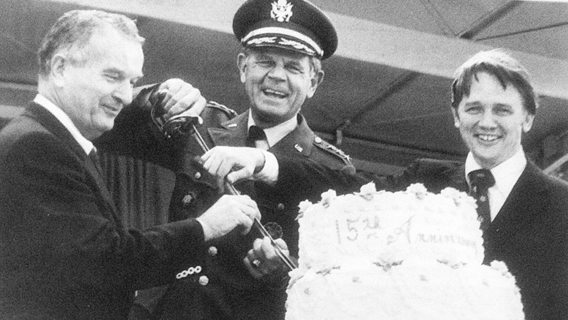 Three men cut a ceremonial cake.