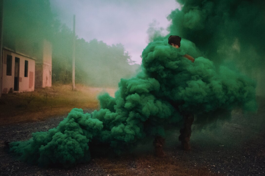 A soldier stands in cloud of green smoke.