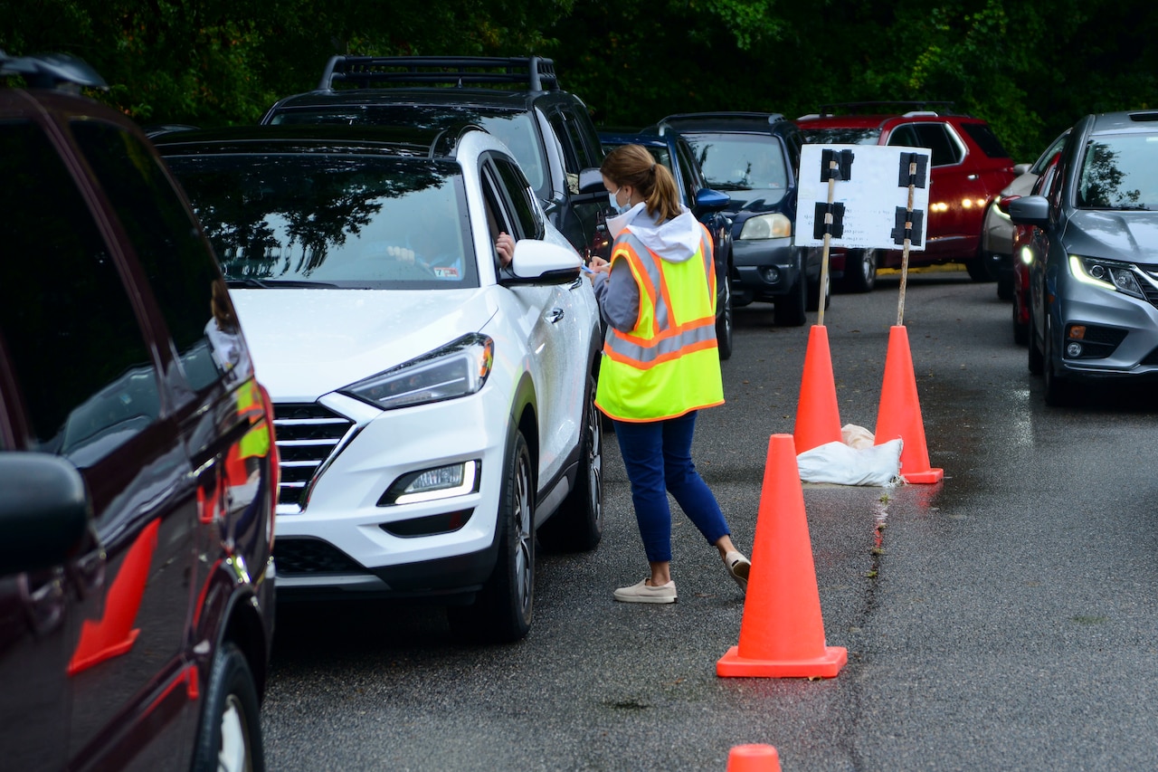 A pharmacist wearing a mask asks patients for medical information at a COVID-19 pharmacy drive-thru.
