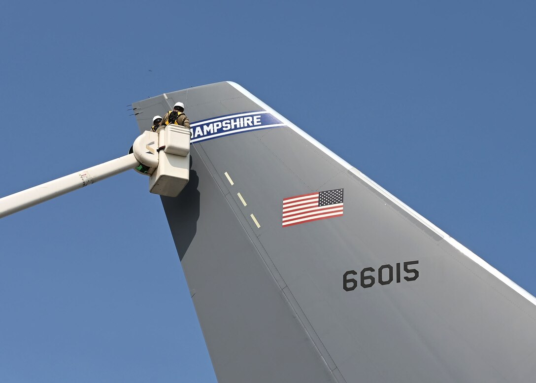 Senior Airman Cory Lewis and Tech Sgt. Jay Cunha, aircraft structural maintainers with the 157th Maintenance Squadron, apply a New Hampshire tail flash to a KC-46 Pegasus on Sept. 16 at Manchester-Boston Regional Airport. The basic font style is similar to that used by the New England Patriots. Photo by Staff Sgt. Charles Johnston, deputy state PAO.