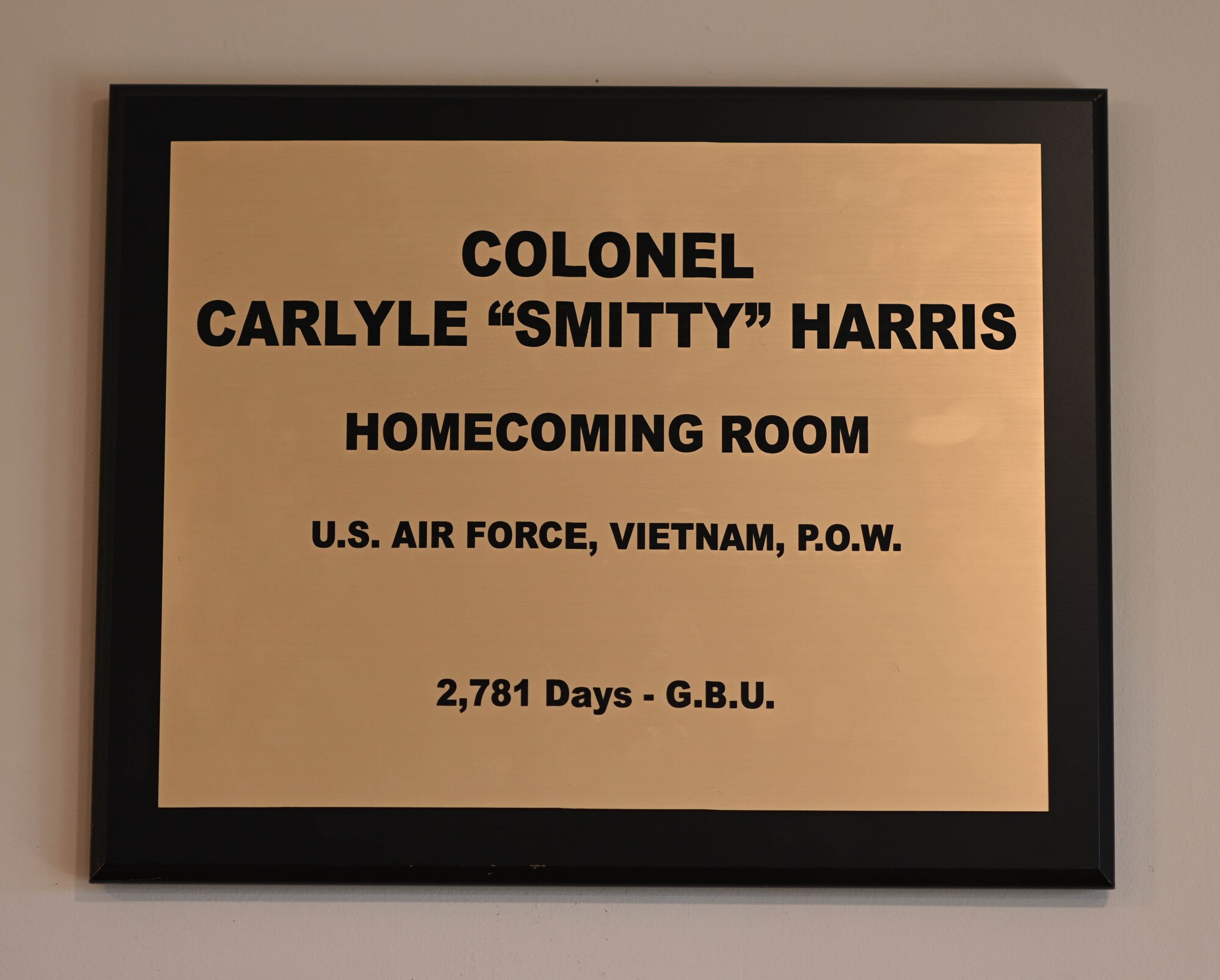 A plaque with Ret. Col. Carlyle “Smitty” Harris’ name is placed above a room dedicated to Harris. Harris and other POWs would use a tap code to tap the acronym “G.B.U.”, which stands for “God Bless You”. (U.S. Air Force photo by Airman 1st Class Davis Donaldson)