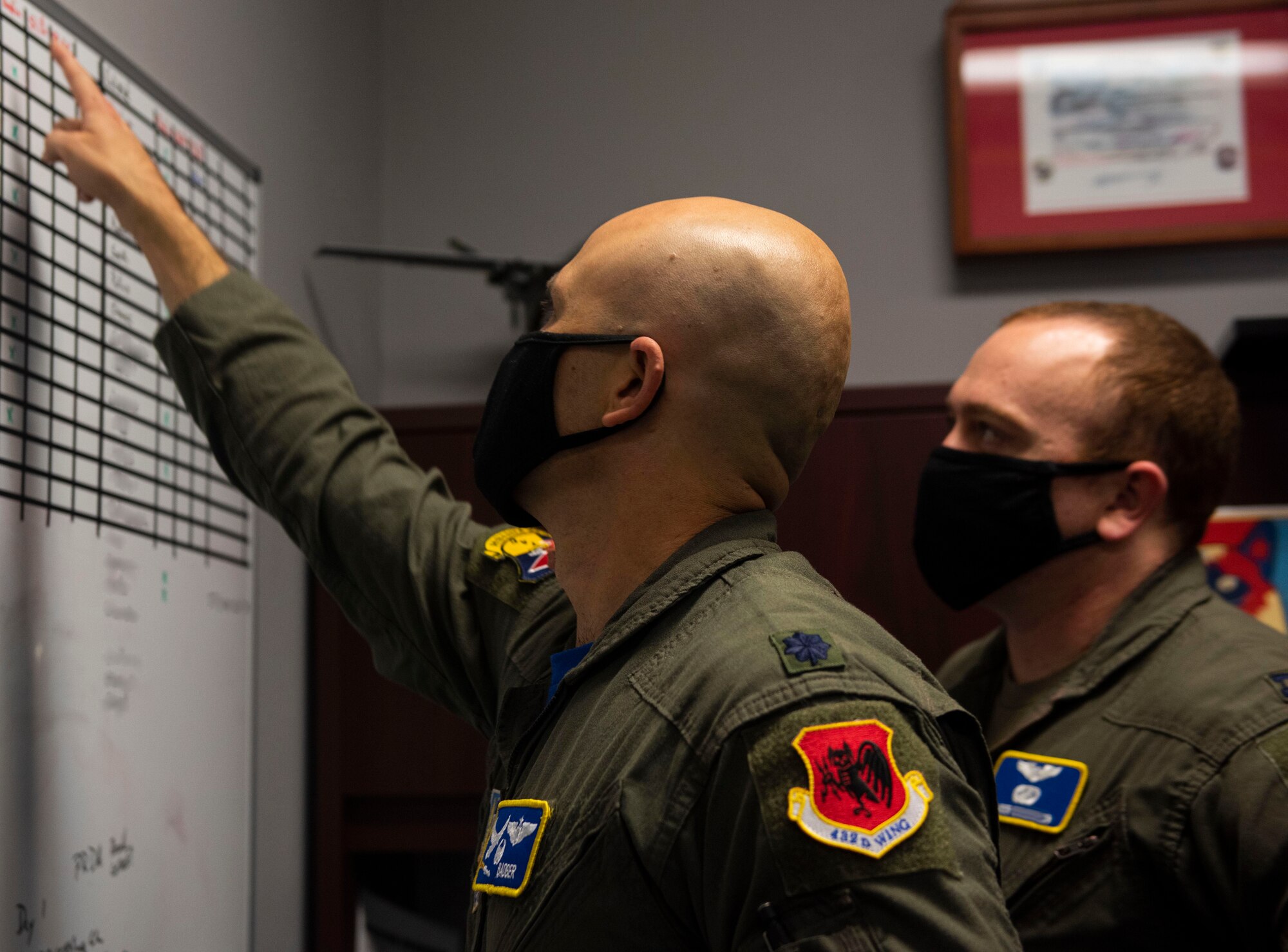 Lt. Col. Robert points at a whiteboard while talking to an airman in the 15th Attack Squadron.