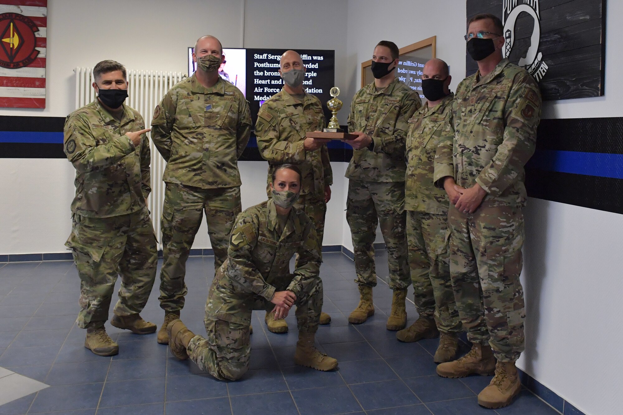 A group of Airmen posing for a photo with a trophy.