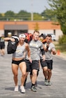 men and women carrying a heavy bean bag.