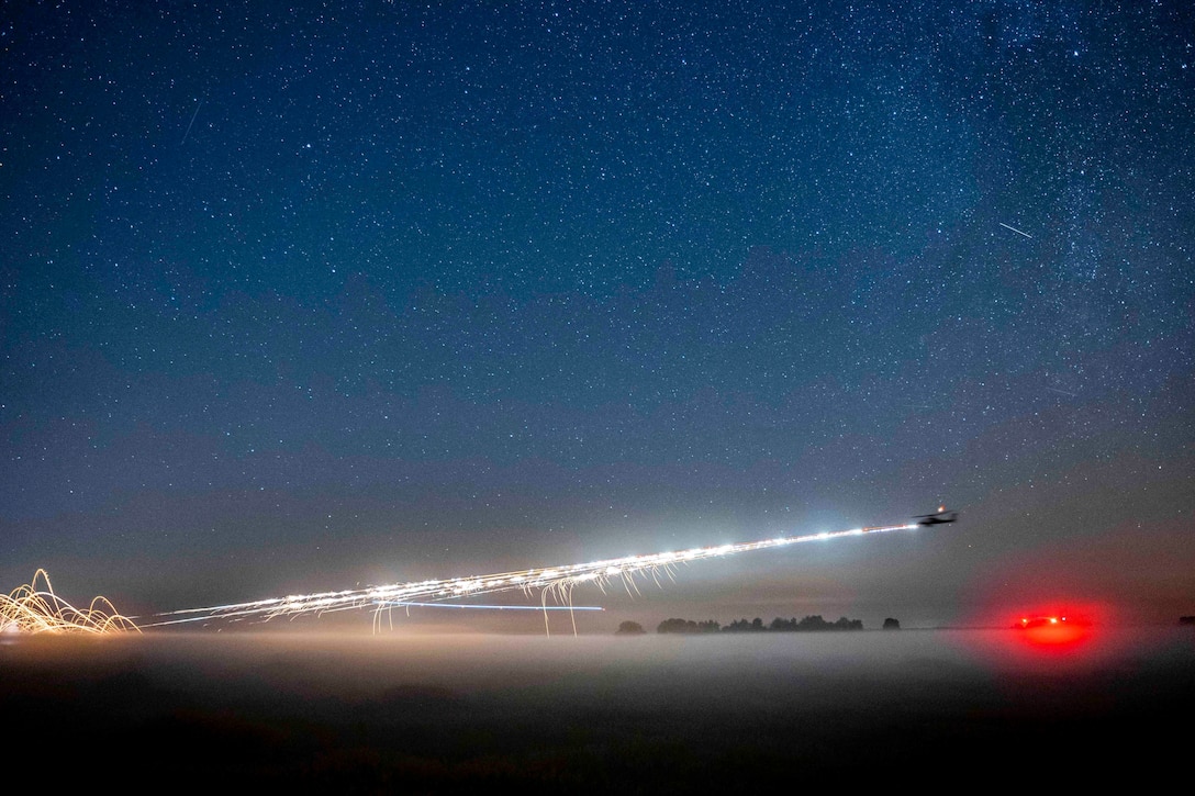 A helicopter fires rockets at night.