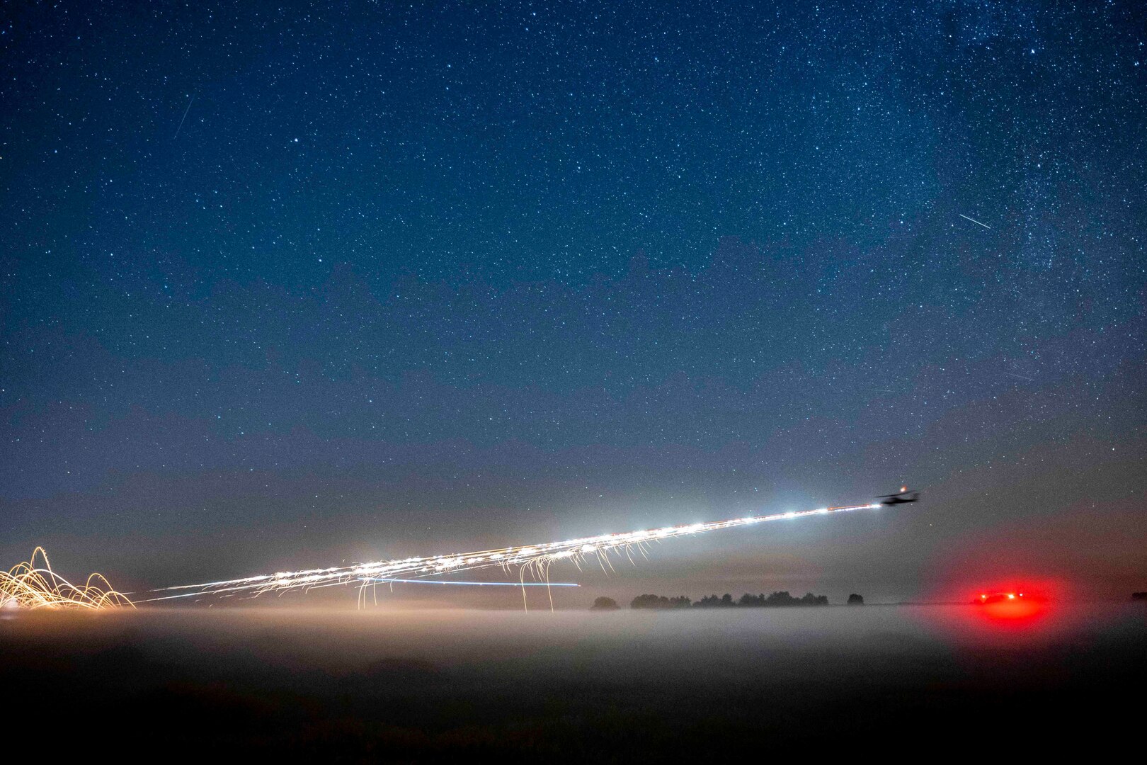 A helicopter fires rockets at night.