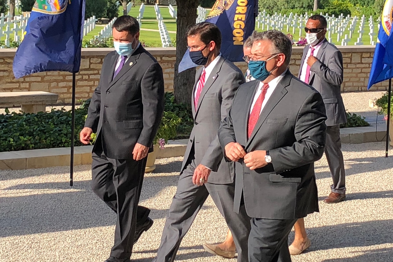 Men walk through a cemetery.