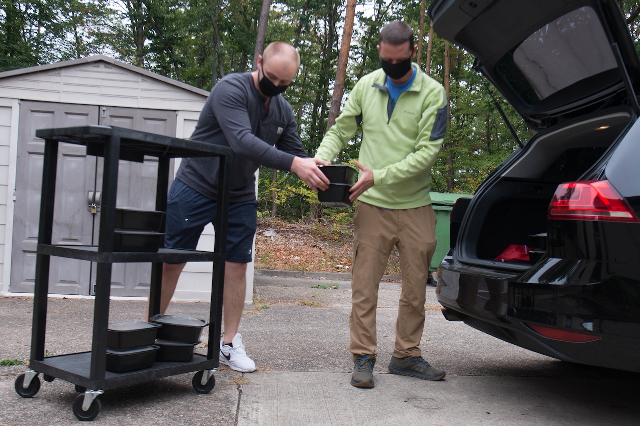 Volunteers loading prepared meals into the back of a vehicle.