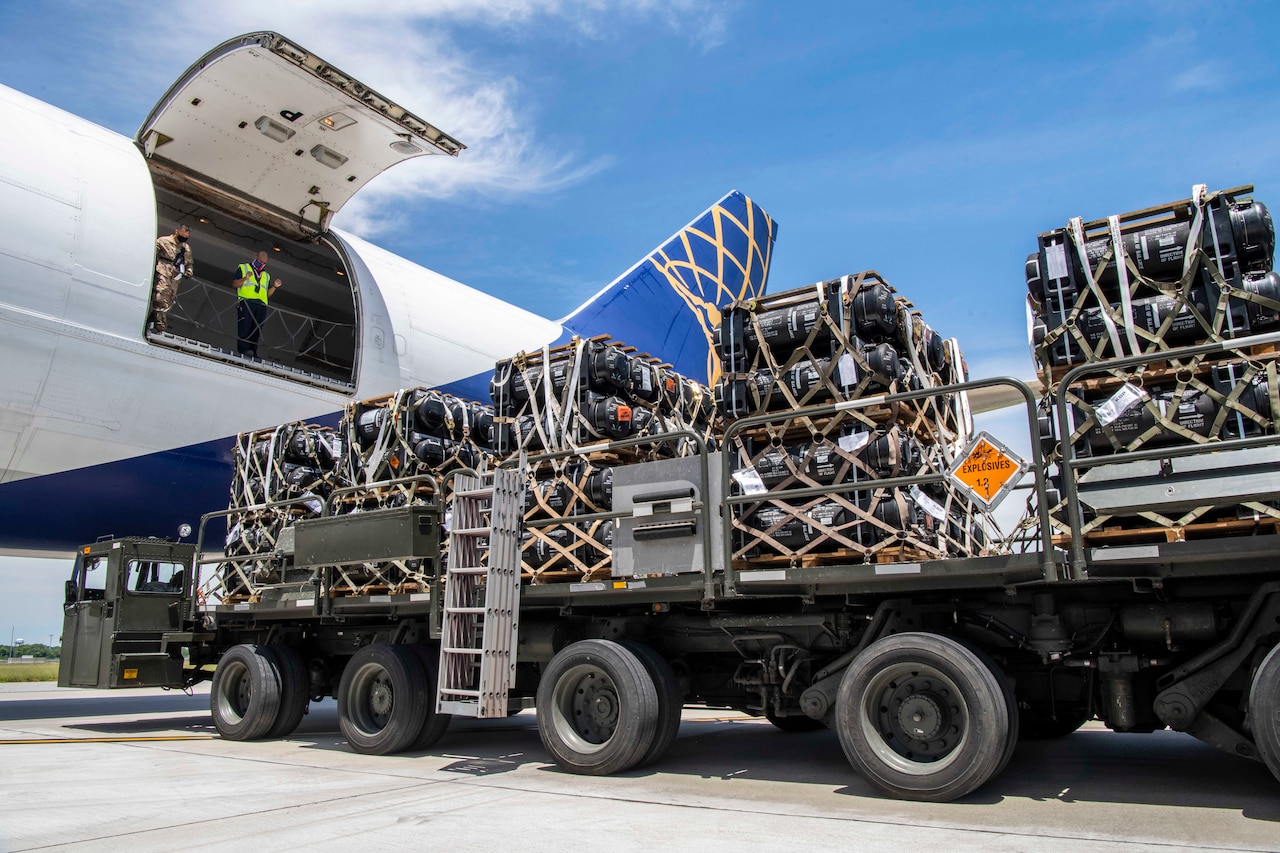 A large loader truck with cargo is backed up to an aircraft.