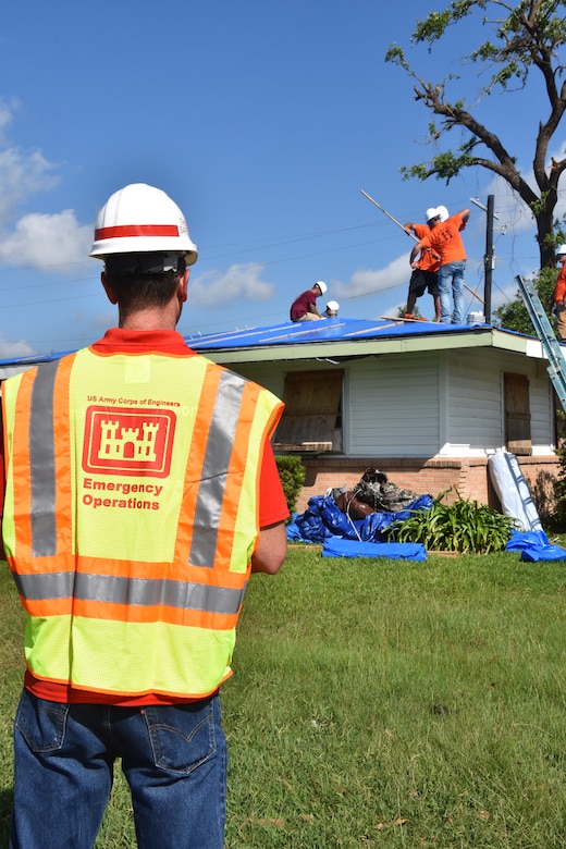 IN THE PHOTO, a U.S. Army Corps of Engineers Blue Roof Mission Assessor observes contractors as they install temporary roofing for the 5,000th homeowner to receive a ‘blue roof’ during Hurricane Laura recovery efforts. Using satellite and fixed-wing imagery allows USACE Assessors anywhere in the world to conduct assessments, but if for some reason imagery is unclear, an evaluator will conduct a physical review of the roof to ensure an accurate assessment is conducted. (USACE photo by George Stringham)