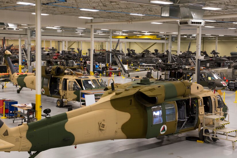 A large warehouse facility contains more than a dozen military helicopters.