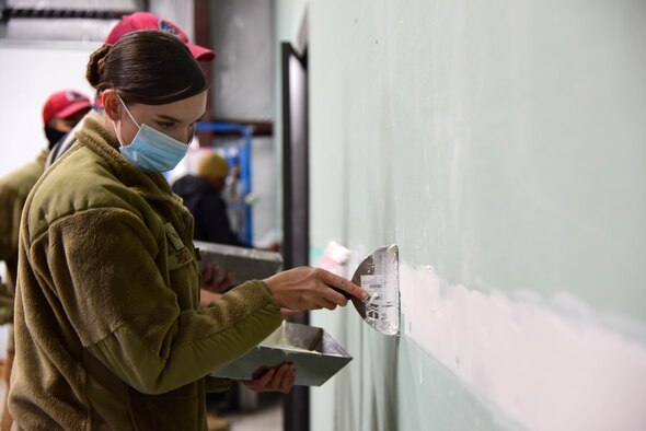 U.S. Air Force Senior Airman Savannah Smith, a 554th Rapid Engineer Deployable Heavy Operational Repair Squadron Engineers (RED HORSE) structures journeyman, applies joint compound to a building partition at Eielson Air Force Base, Alaska, Sept. 10, 2020.