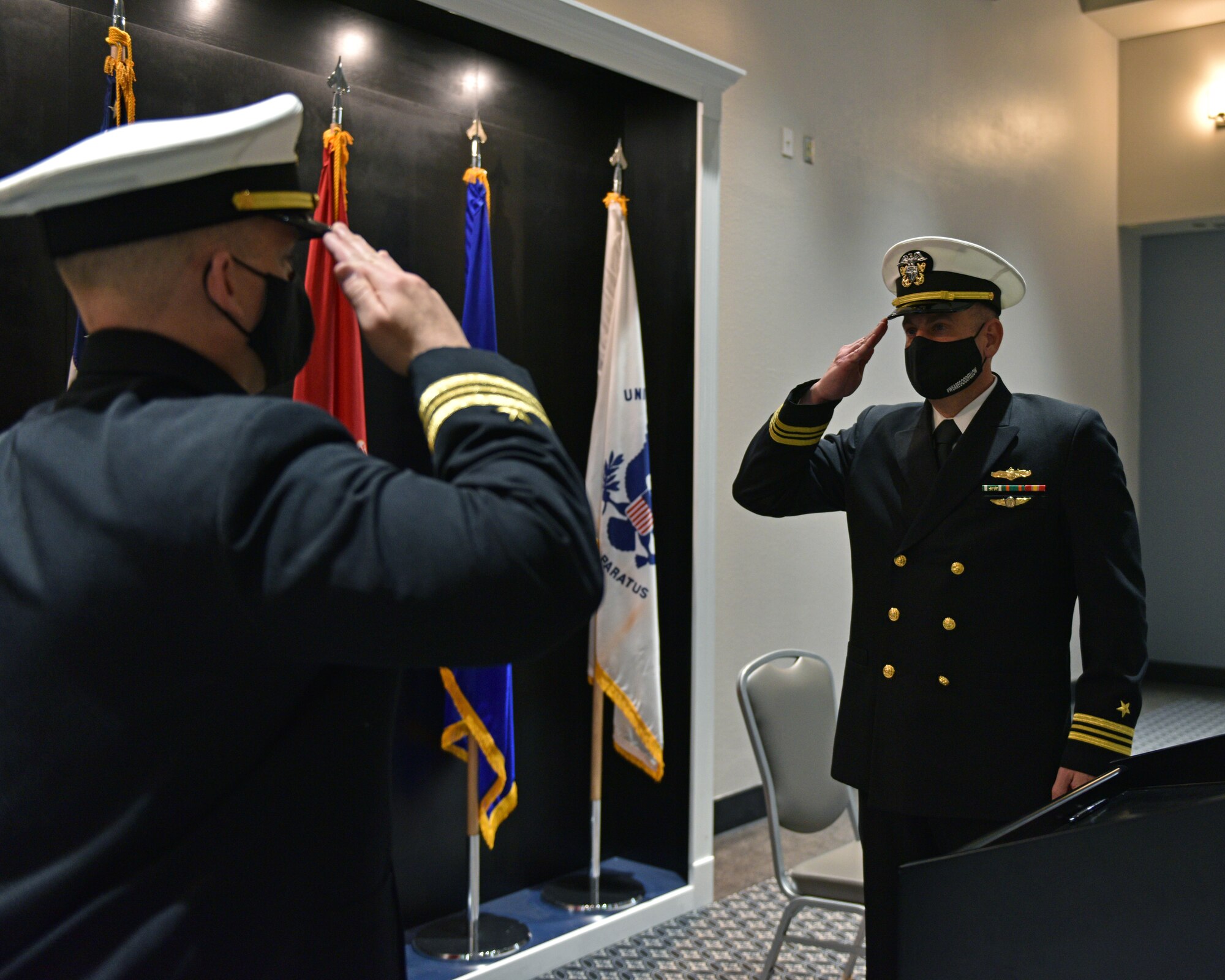 U.S. Navy Lt. Cmdr. John Allen, departing Navy Center for Information Warfare Training Detachment Goodfellow officer in charge, exchanges salutes with Lt. Cmdr. Mark Wess, Navy CIWT Detachment Goodfellow incoming commanding officer, during the Change of Charge ceremony at the Event Center on Goodfellow Air Force Base, Texas, March 31, 2021. This change of charge ceremony was a time to honor military tradition and signified the transfer of authority. (U.S. Air Force photo by Senior Airman Ashley Thrash)