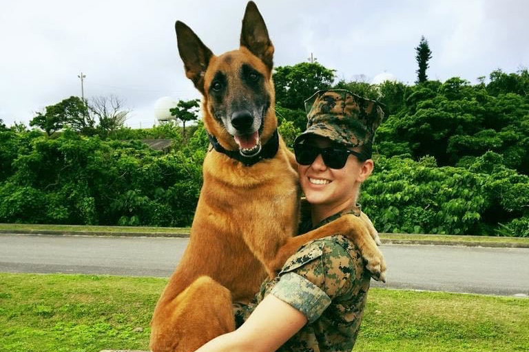 Marine Corps Sgt. Jenna Cauble poses for a photo with Bbutler, a military working dog.