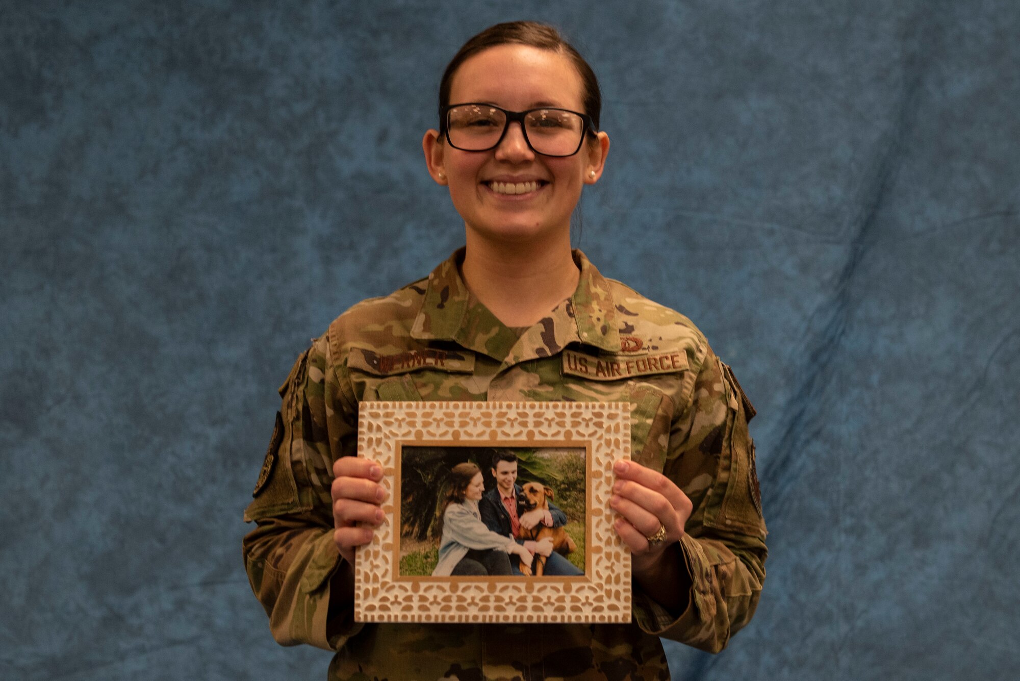 Airman 1st Class Abby Werner 47th Operations Support Squadron air traffic controller, poses with a photo of her and her husband and dog, at Laughlin Air Force Base, Texas, Jan. 13, 2021. Abby and her husband are both serving and are stationed at Laughlin. (U.S. Air Force photo by Airman 1st Class David Phaff)