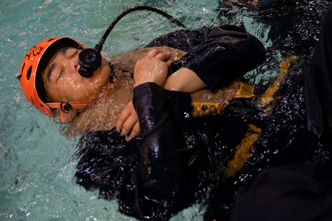 A Marines submerges himself underwater while using an air tank.