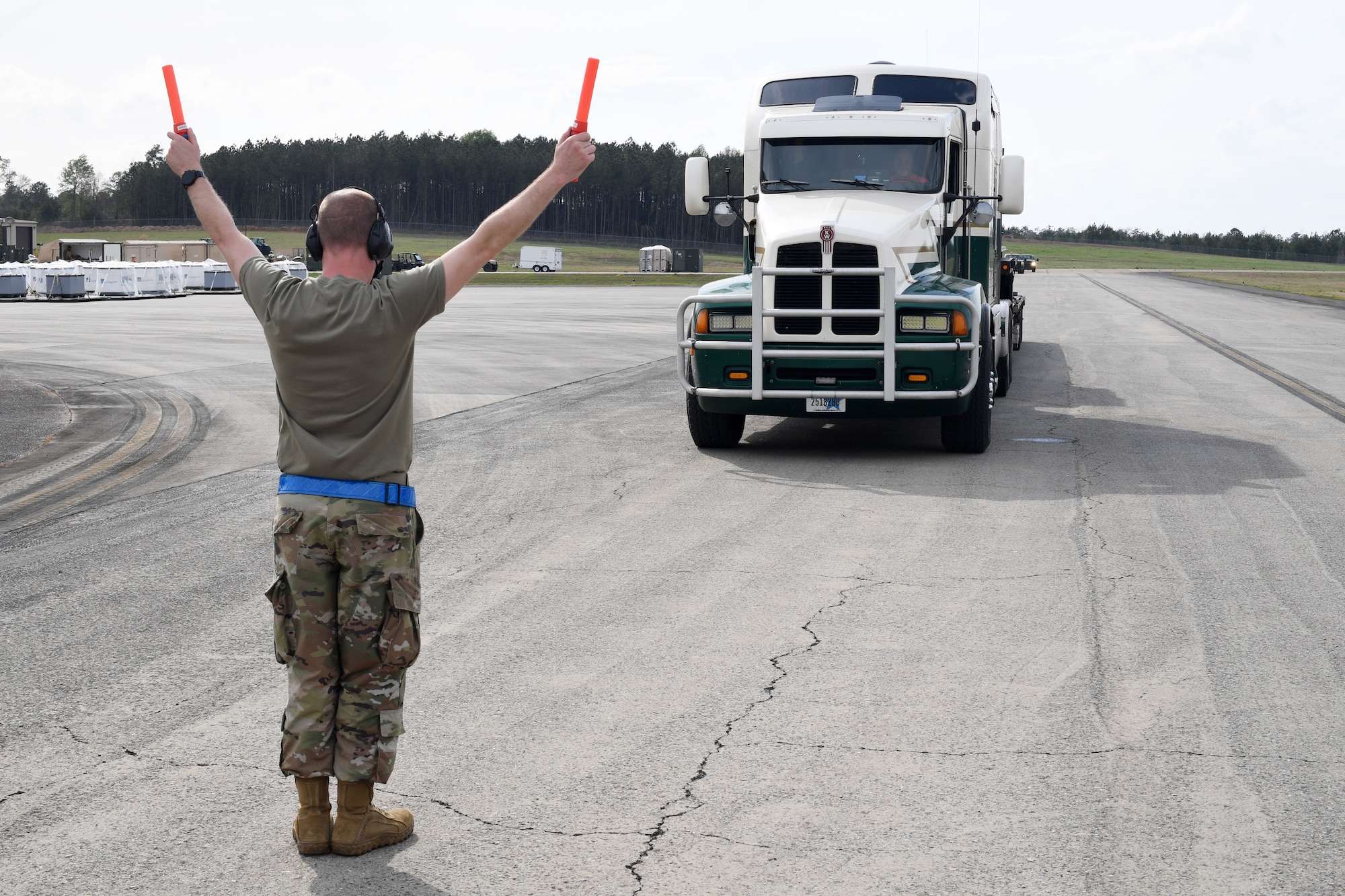 U.S. Air Force Master Sgt. Joshua Atkinson, 321st Contingency Response Squadron maintenance flight chief, marshals in a simulated C-130 Hercules aircraft March 27, 2021, at Camp Shelby, Mississippi. For Exercise Turbo Distribution, the U.S. Transportation Command established a joint task force port opening aerial port of debarkation capability to respond to a simulated humanitarian aid and disaster relief request from the fictional country of Bengalia. (U.S. Air Force photo by Tech. Sgt. Luther Mitchell)
