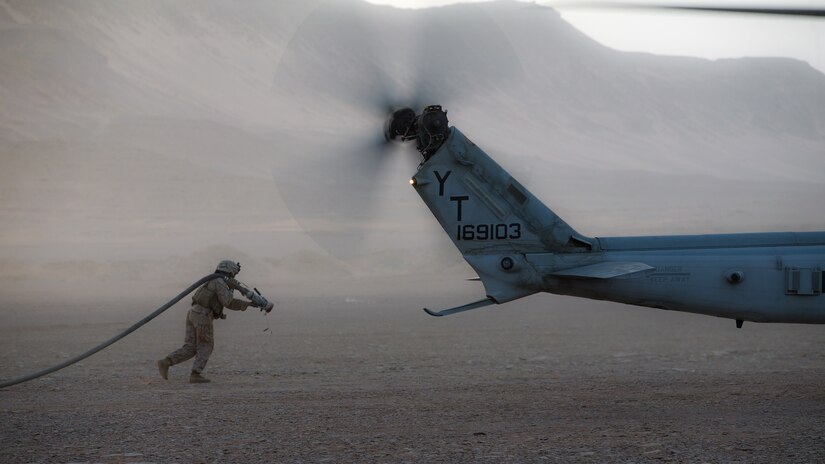 A U.S. Marine carries a fuel hose to a UH-1Y Venom at a forward arming and refueling point during a theater amphibious combat rehearsal in Tabuk, Kingdom of Saudi Arabia, March 9.