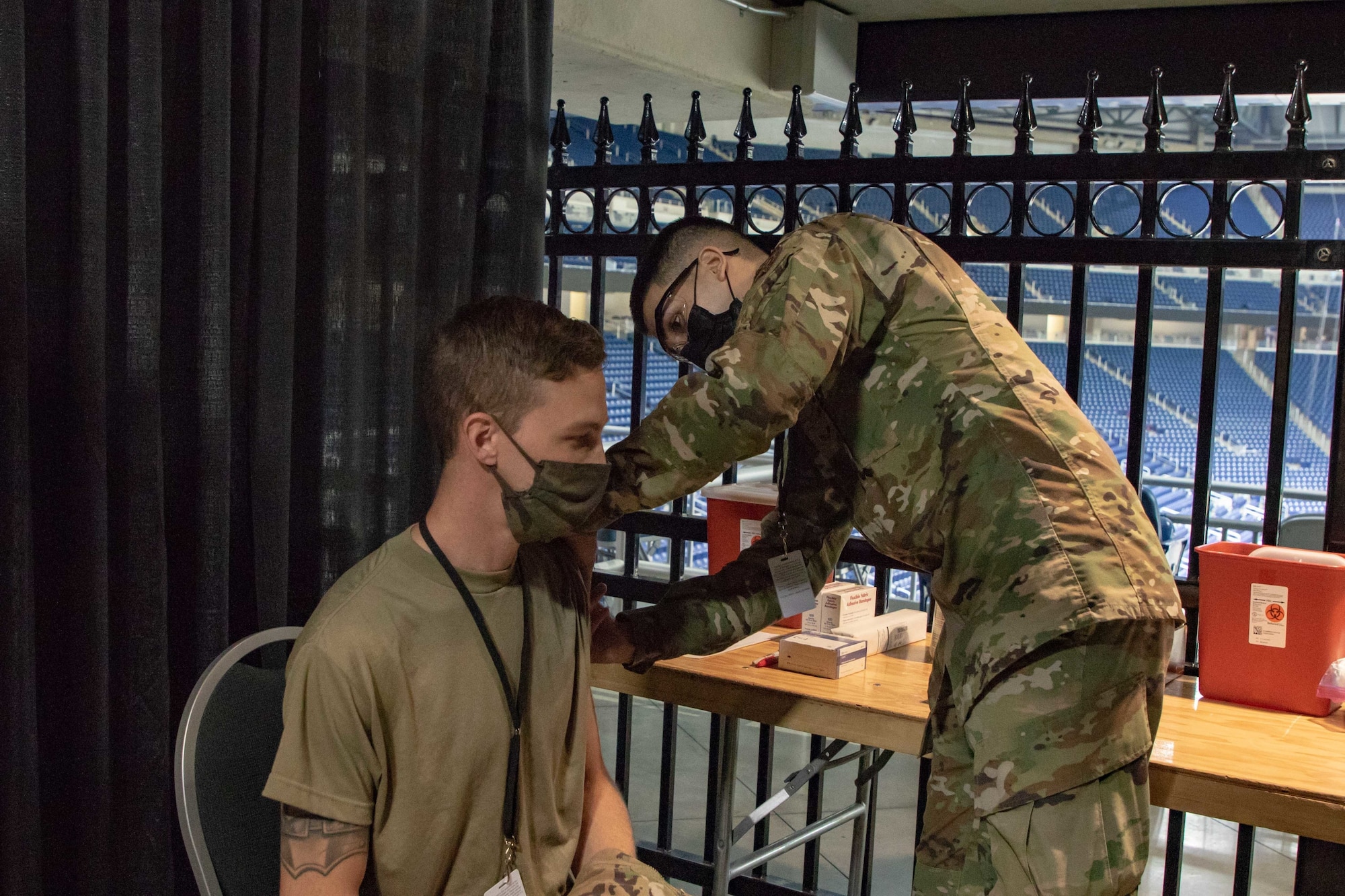 U.S. Air Force Senior Airman Dominic Patel, a Jonesboro, Arkansas, native and Aerospace Medical service member, part of the 88th Health Care Operations Squadron, stationed at Wright-Patterson Air Force Base, Ohio, acts out the vaccination procedure on Airman 1st Class Andrew Trempus, a Tyler, Texas, native and Aerospace Propulsion service member, part of the 35th component maintenance squad, stationed at Davis-Monthan Air Force Base, Arizona, at the state-run, federally-supported Ford Field COVID-19 Community Vaccination Center, March 22, 2021. Both Airmen are currently assigned to the 1st Detachment, 64th Air Expeditionary Group. The exercise covered all aspects of what a community member would experience upon arrival, through the entire vaccination process, at the CVC. U.S. Northern Command, through U.S. Army North, remains committed to providing flexible Department of Defense support to the whole-of-government COVID-19 response. (U.S. Army photo by Spc. Andrew Wash, 5th Mobile Public Affairs Detachment)