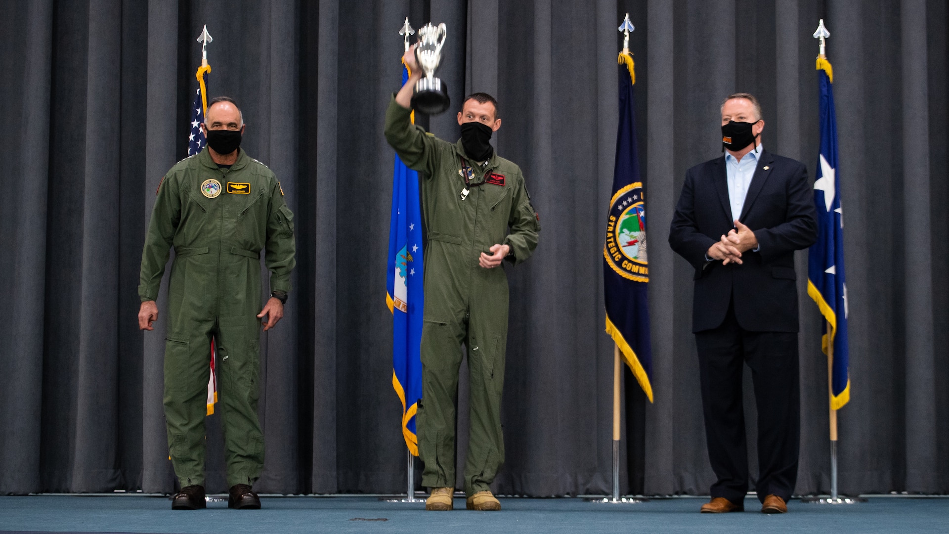 Lt. Col. Christopher Duff, center, raises the Omaha Trophy after receiving the award from Adm. Charles Richard, U.S. Strategic Command commander, left, and Mr. Tim Burke, right, Strategic Command Consultation Committee chairman, at Barksdale Air Force Base, Louisiana,  March 30, 2021. First awarded by the Strategic Air Command Consultation Committee  in 1971, the Omaha trophy is presented to units across the command in four official categories: intercontinental ballistic missile squadron, ballistic missile submarine, strategic bomber squadron, and global operations squadron. (U.S. Air Force photo by Airman 1st Class Jacob B. Wrightsman)