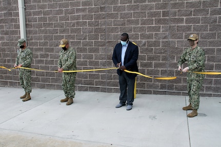 Capt. Tres Meek, commanding officer, Naval Facilities Engineering Systems Command Mid-Atlantic (far left); Capt. Vince Baker, commanding officer, Naval Station (NAVSTA) Norfolk (left); Lloyd Young, Project Manager for Tazewell Contracting (right); and Capt. Dianna Wolfson, commander, Norfolk Naval Shipyard (far right) participate in a ribbon-cutting ceremony to officially present the new Submarine Universal Modular Mast (UMM) Maintenance Tower onboard NAVSTA Norfolk, March 31. The new facility allows the Navy to provide repairs and maintenance for Hampton Roads-based submarines to the UMM, which is an integrated system that houses the submarine’s periscope, antennas and sensors.