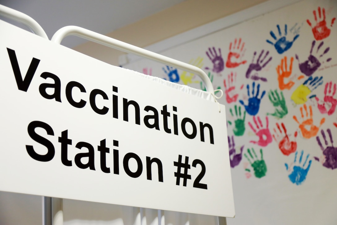 An image shows a COVID-19 vaccine station sign.