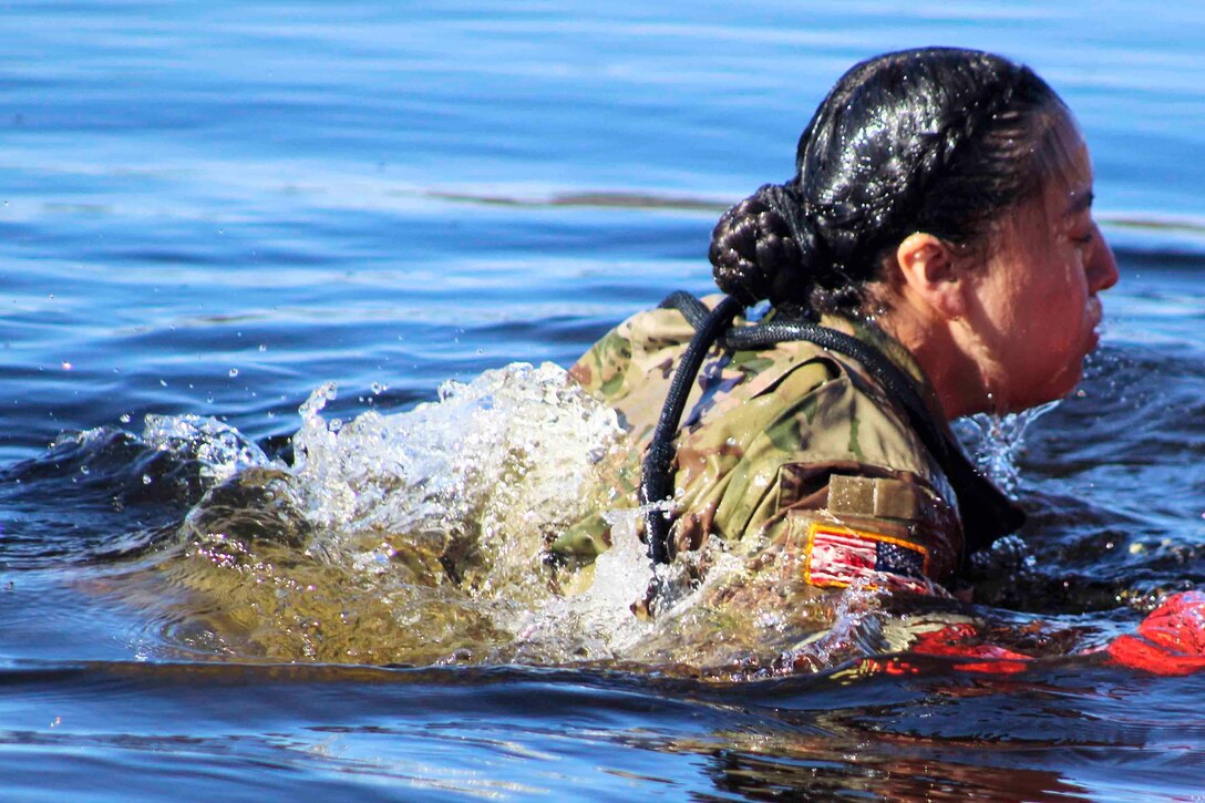 A service member moves in water up to her shoulders.