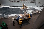 Sailors aboard the Arleigh Burke-class guided-missile destroyer USS Roosevelt (DDG 80) receive pallets of food stores during a replenishment-at-sea with the dry cargo ship USNS William McClean (T-AKE 12), April 1, 2021.