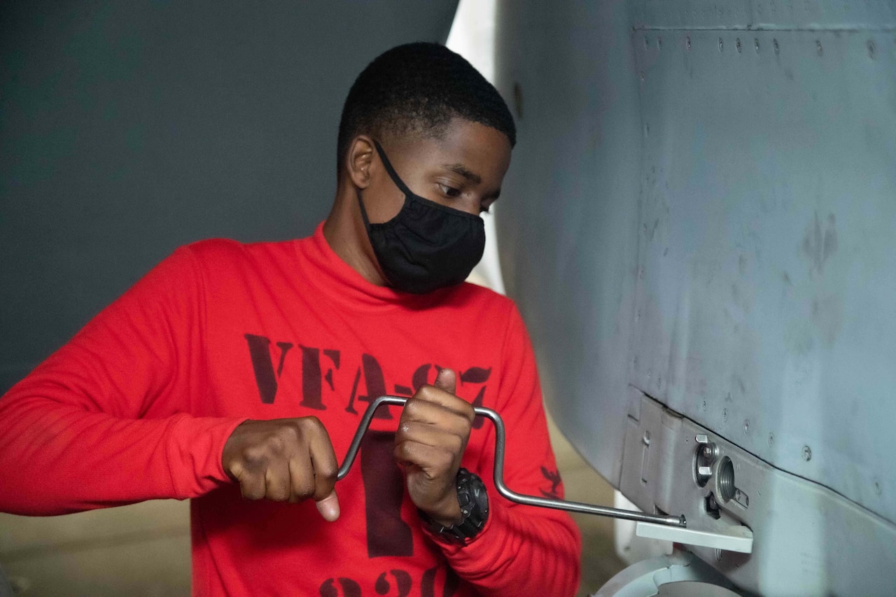 A man applies a tool to the side of an aircraft.