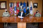 Robert Naething, U.S. Army North (Fifth Army) deputy to the commanding general, signs a proclamation honoring April as the Month of the Military Child on Joint Base San Antonio, while Brig. Gen. Caroline M. Miller, 502d Air Base Wing and JBSA commander, left, and Rear Adm. Cynthia Kuehner, Naval Medical Forces Support Command commander, right, look on.