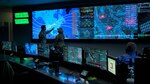 Military personnel stand in an operations center.
