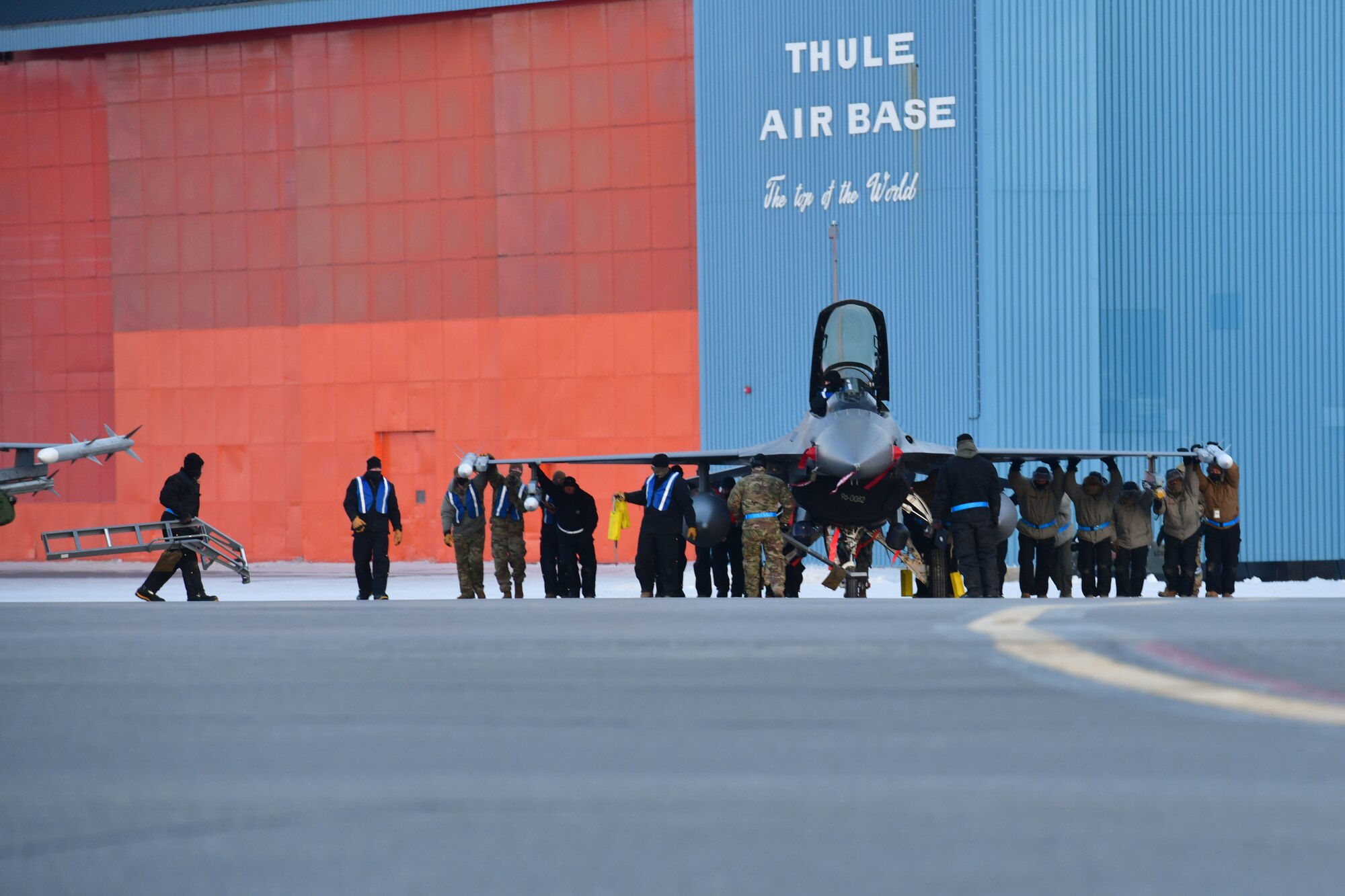 U.S. Air Force Airmen from the 148th Aircraft Maintenance Squadron utilize a manual tow-bar to position an F-16 at Thule Air Base, Greenland during North American Aerospace Defense Command’s Arctic air defense exercise, Amalgam Dart 21-2, March 22, 2021.