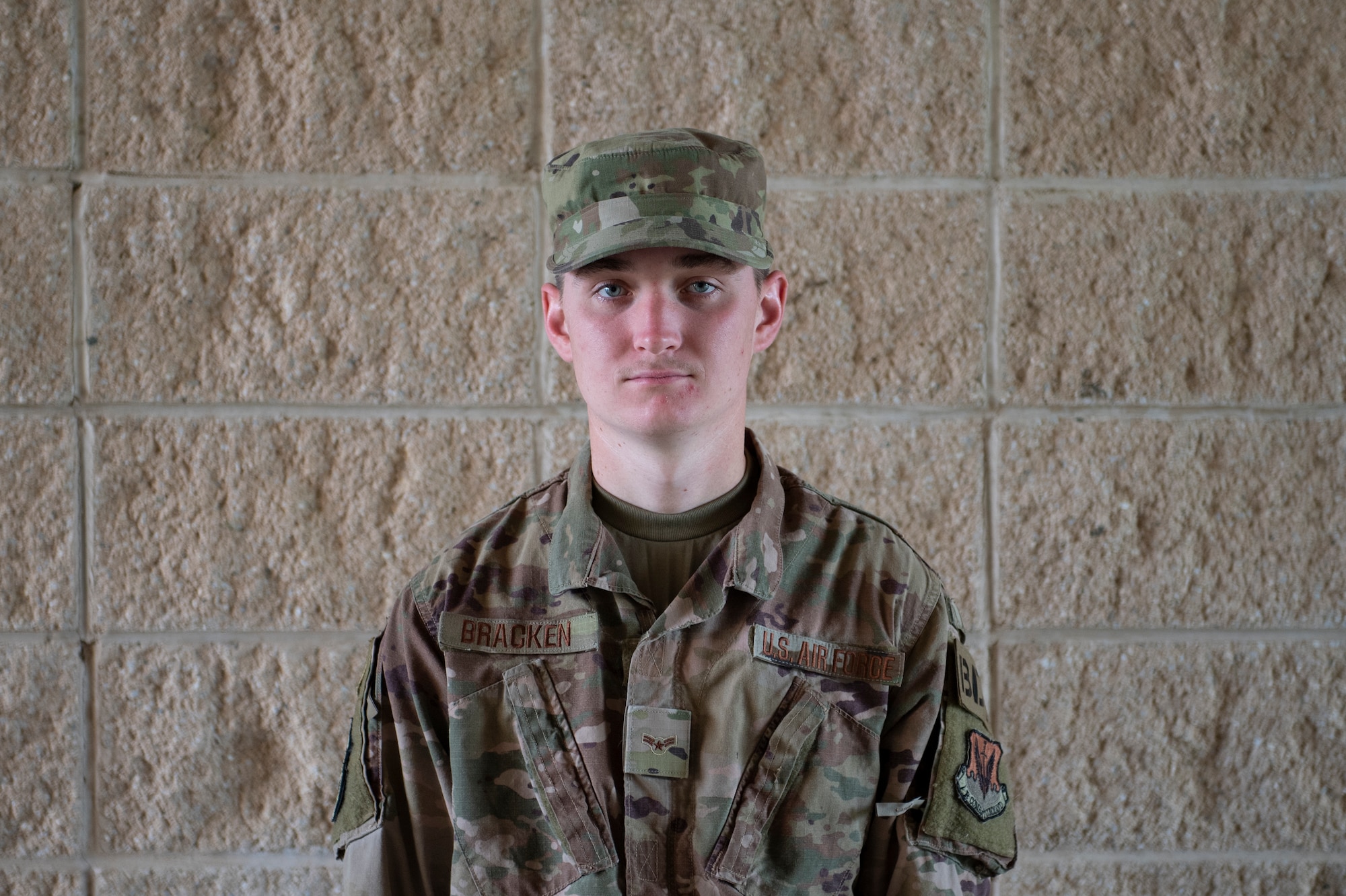 A photo of an Airman in front of a brick wall.