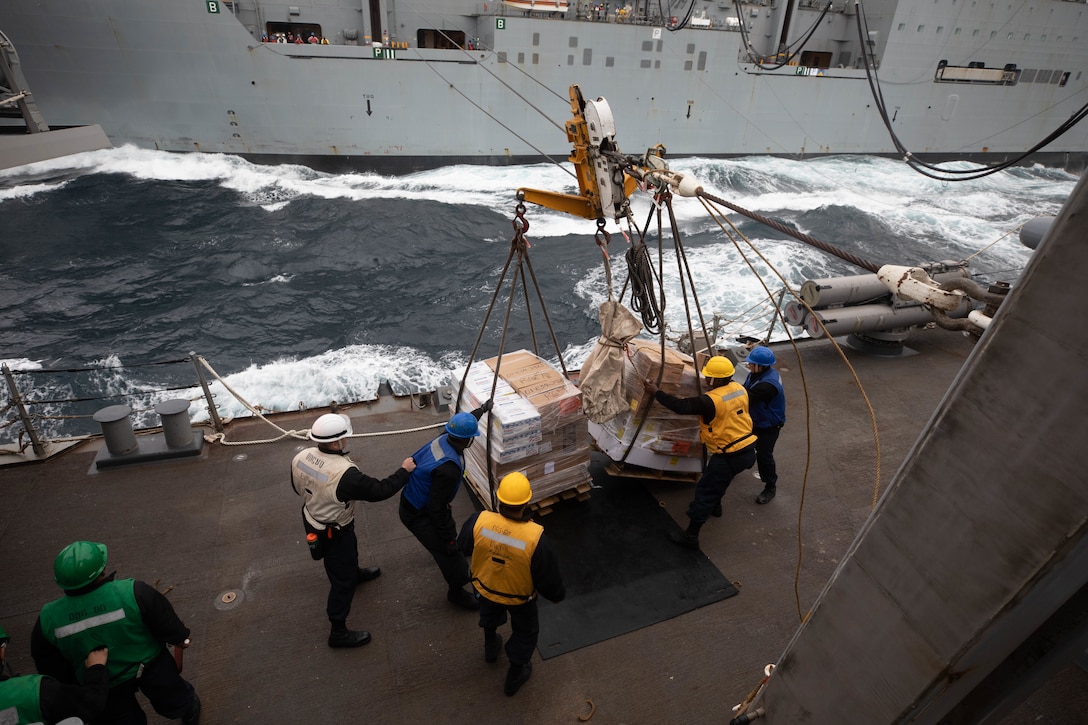 Sailors aboard the Arleigh Burke-class guided-missile destroyer USS Roosevelt (DDG 80) receive pallets of food stores during a replenishment-at-sea with the dry cargo ship USNS William McClean (T-AKE 12), April 1, 2021.